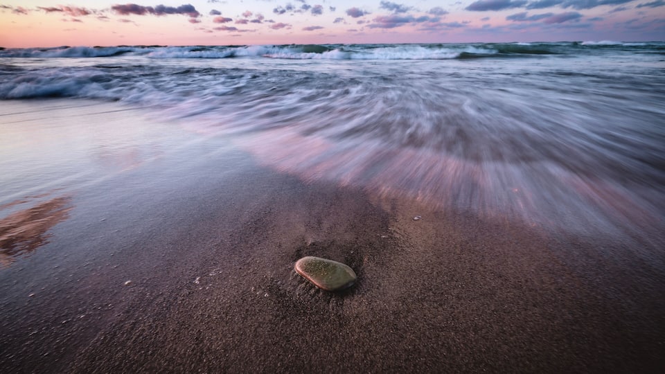 A beach with waves and a sunset.
