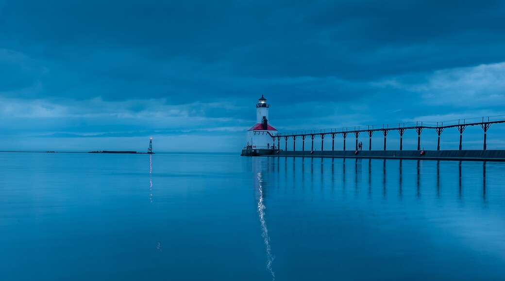 still water long exposure image of stormclouds pier and lighthouse at michigan city indiana