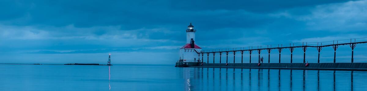 still water long exposure image of stormclouds pier and lighthouse at michigan city indiana