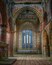 An interior of a historic building with arched brick walls and a large stained glass window.