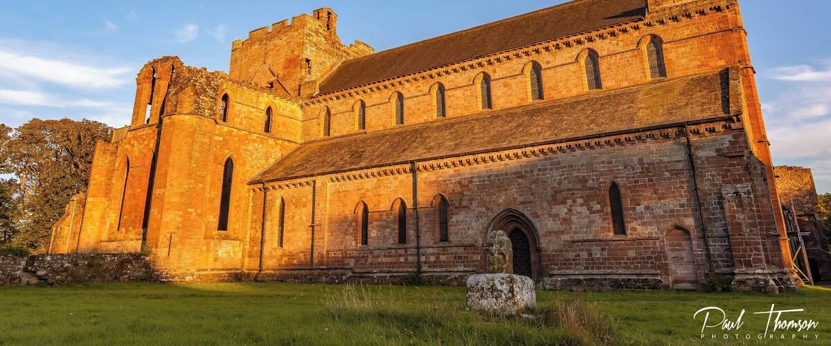 An ancient stone building with arched windows and a large tower.