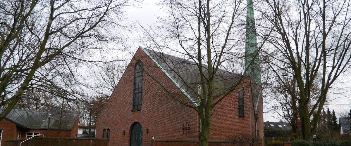 A brick church with a tall steeple and a large window.