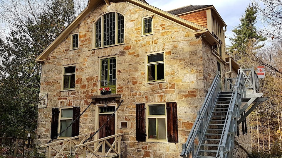 A stone building with a wooden staircase and a small garden.