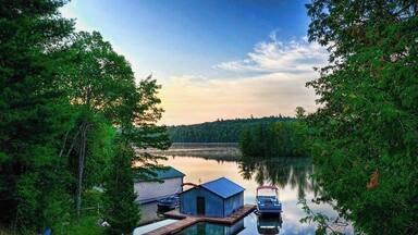 A serene lake with docked boats, a wooden pier, and a small cabin.