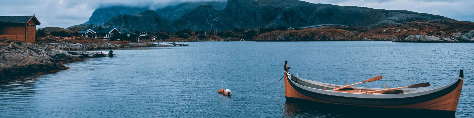 Dønna Mountain in Northern Norway is seen from the sea level with a row boat in the foreground.
