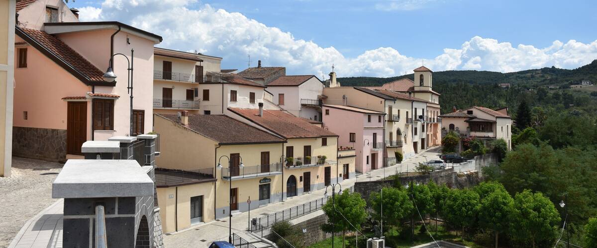 A hillside village with pastel-colored buildings, a church, and a clear blue sky.