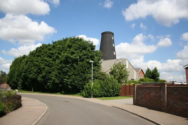 A church with a tall tower, surrounded by trees and a paved road.