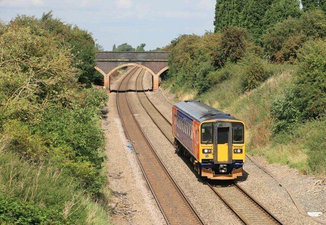A train on railway tracks with a bridge in the background.