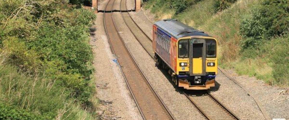 A train on railway tracks with a bridge in the background.