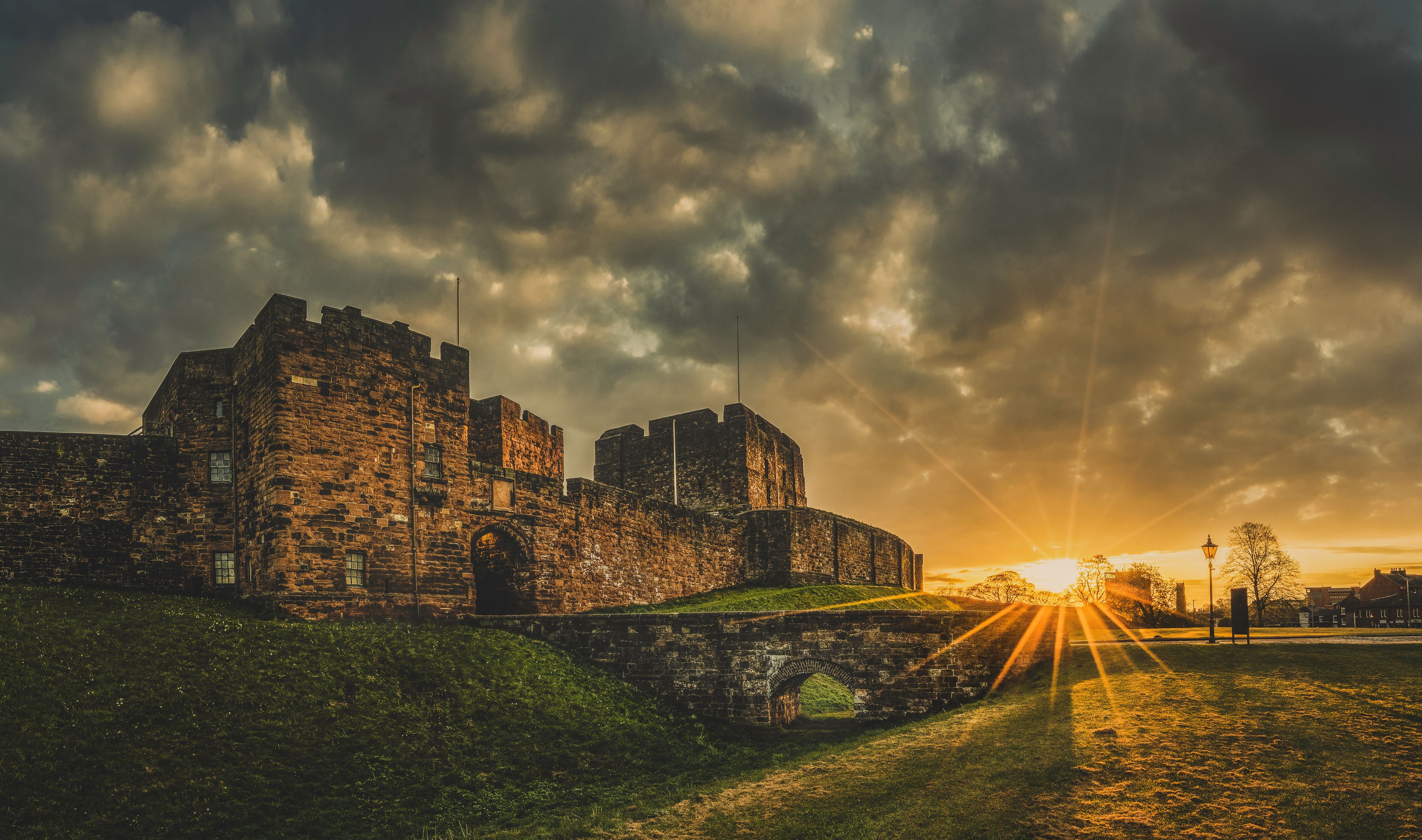 Un castillo de piedra histórico con un foso, bajo un cielo crepuscular espectacular.