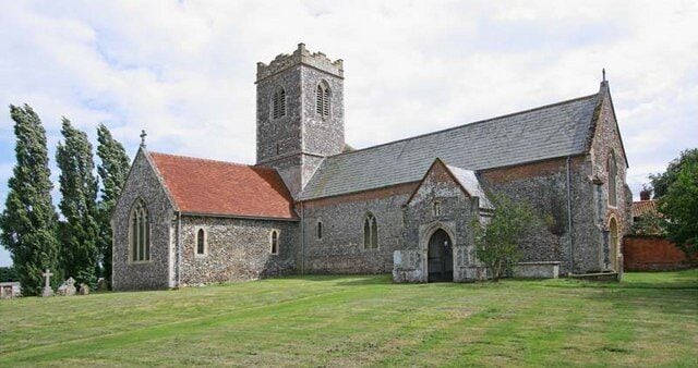 A historic church with a stone facade, a red-tiled roof, and a bell tower.