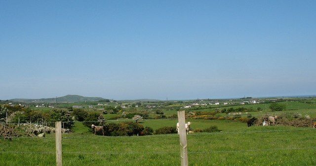View westwards across grazing land in the direction of the Llanfechell-Mynydd Mechell road The mountain in the background is Mynydd y Garn SH3190.