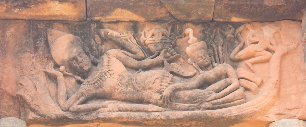 A detailed stone carving of a reclining figure with a serpent.