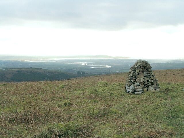 Summit cairn on Cefn Drum Just below the grassy surface of Cefn Drum is a lot of colliery spoil - ample source material for the attractive little cairn. In the distance, the Loughor winds its way out to sea, and the Gower Peninsula juts out along the horizon.