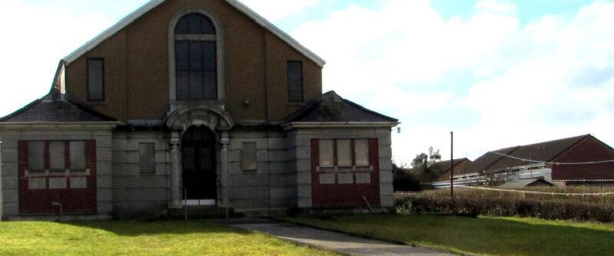 A two-story building with a pitched roof, a central arched entrance, and a symmetrical facade with windows and doors.