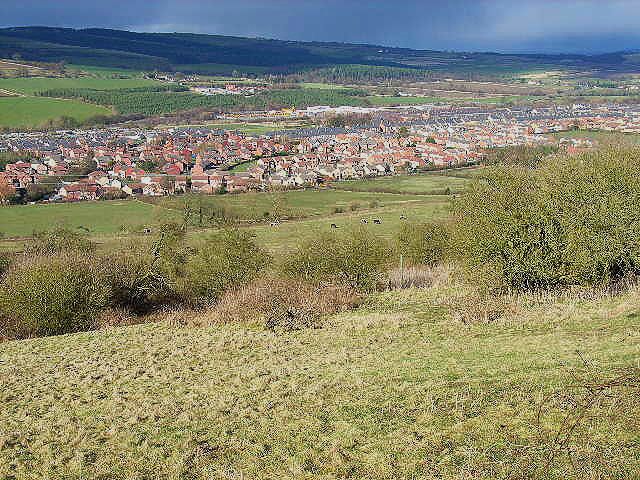 A town nestled in a valley with rolling hills in the background.