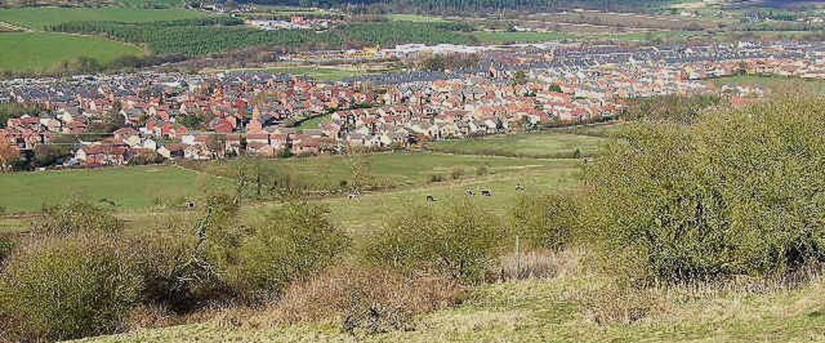 A town nestled in a valley with rolling hills in the background.