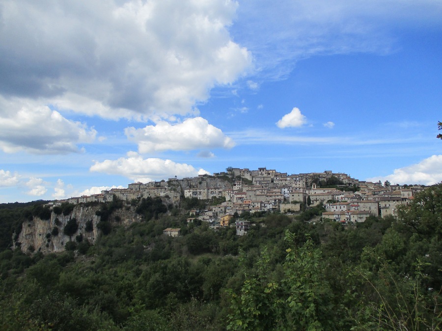 Un pueblo en una ladera con edificios construidos sobre un acantilado, rodeado de vegetación.