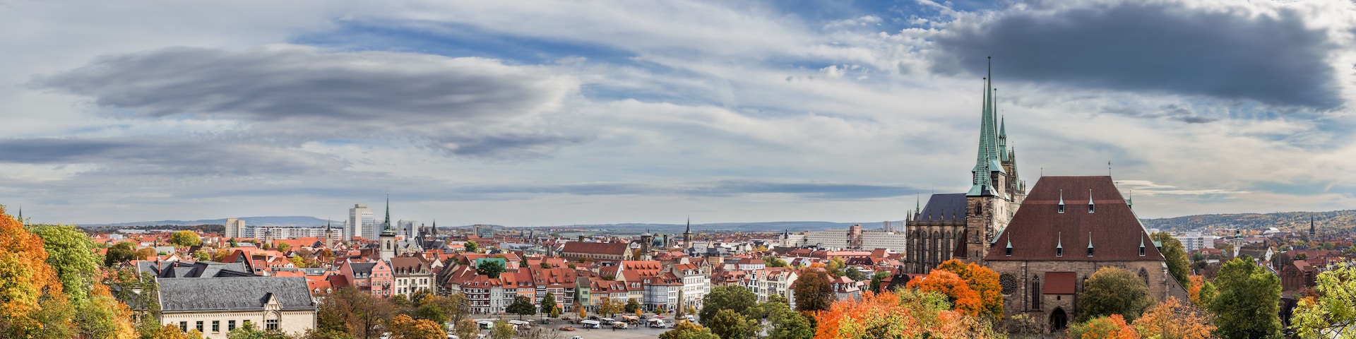 Eine Stadtansicht mit Herbstlaub, historischen Gebäuden und einem markanten Kirchturm.
