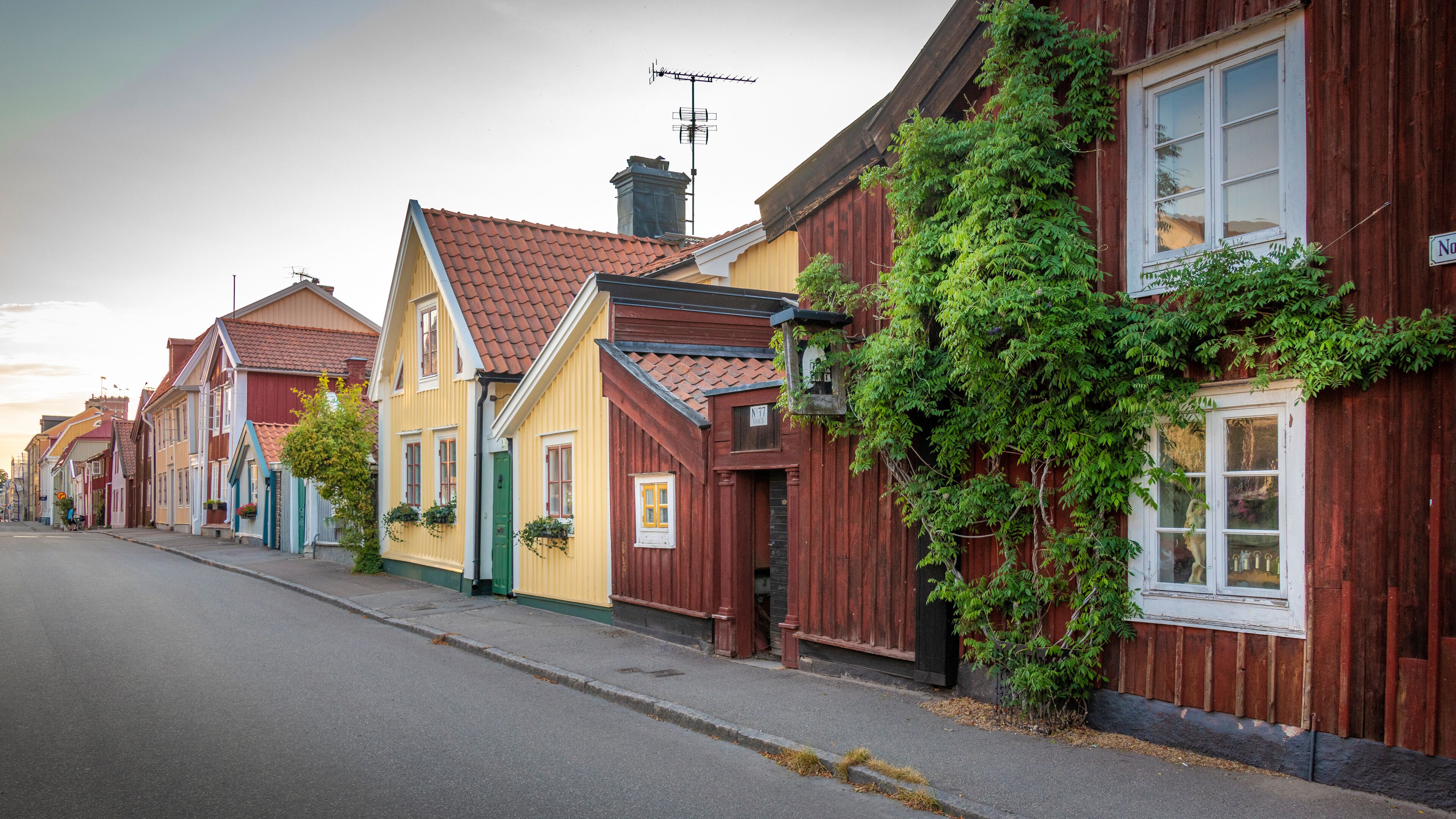 A row of colorful houses with red, yellow, and blue facades, a street, and a clear sky.
