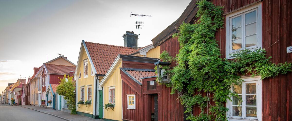 A row of colorful houses with red, yellow, and blue facades, a street, and a clear sky.