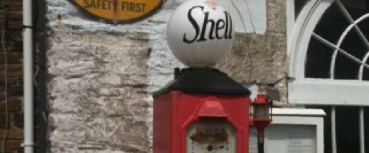 A vintage gas pump with a Shell logo, a sign reading "S. MAWES, TREGONY 101, LONDON 2631, SAFETY FIRST," and a 2/3rd gallon capacity indicator.