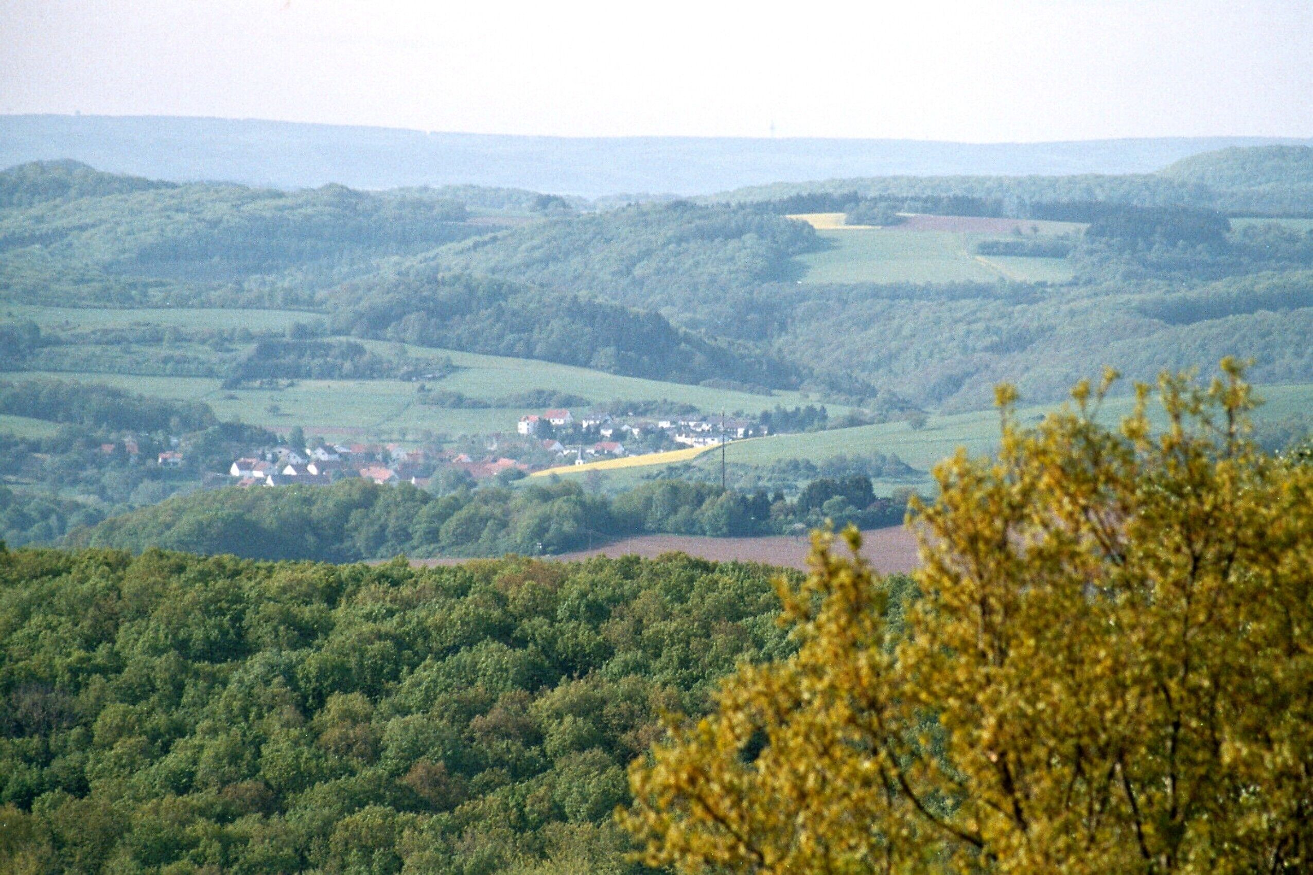 A valley with rolling hills, a small village, and a river.