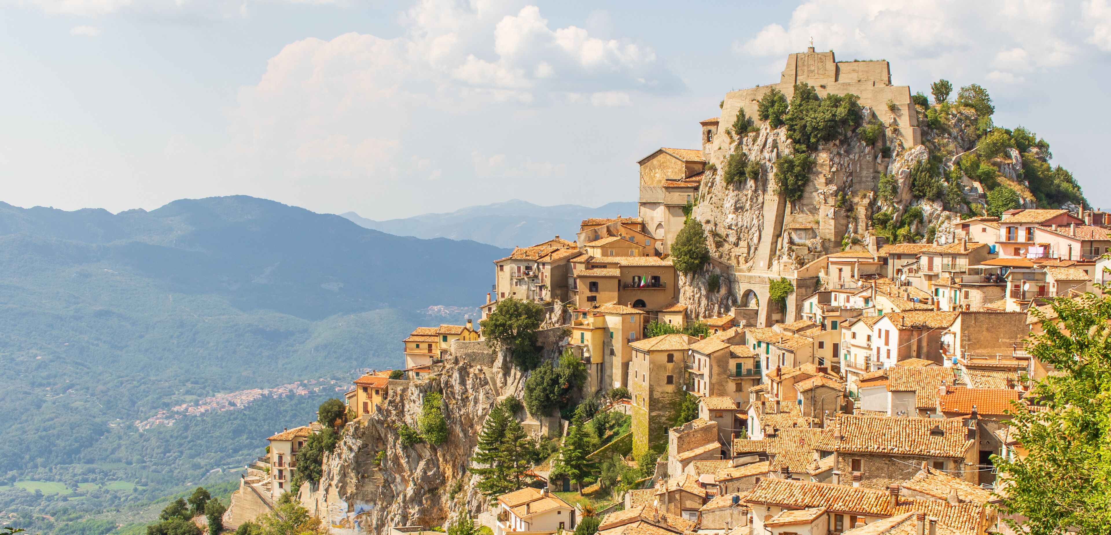 A mountainous town with terracotta-roofed buildings perched on a cliff.