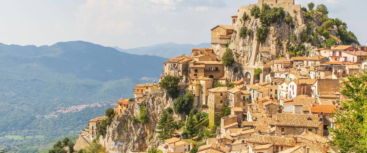 A mountainous town with terracotta-roofed buildings perched on a cliff.