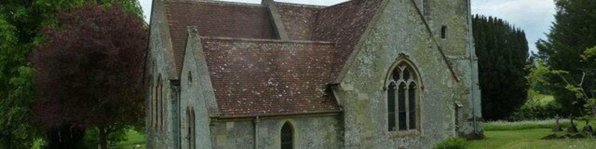 Uma igreja histórica com telhado íngreme, uma torre de sino e uma pequena janela em arco.