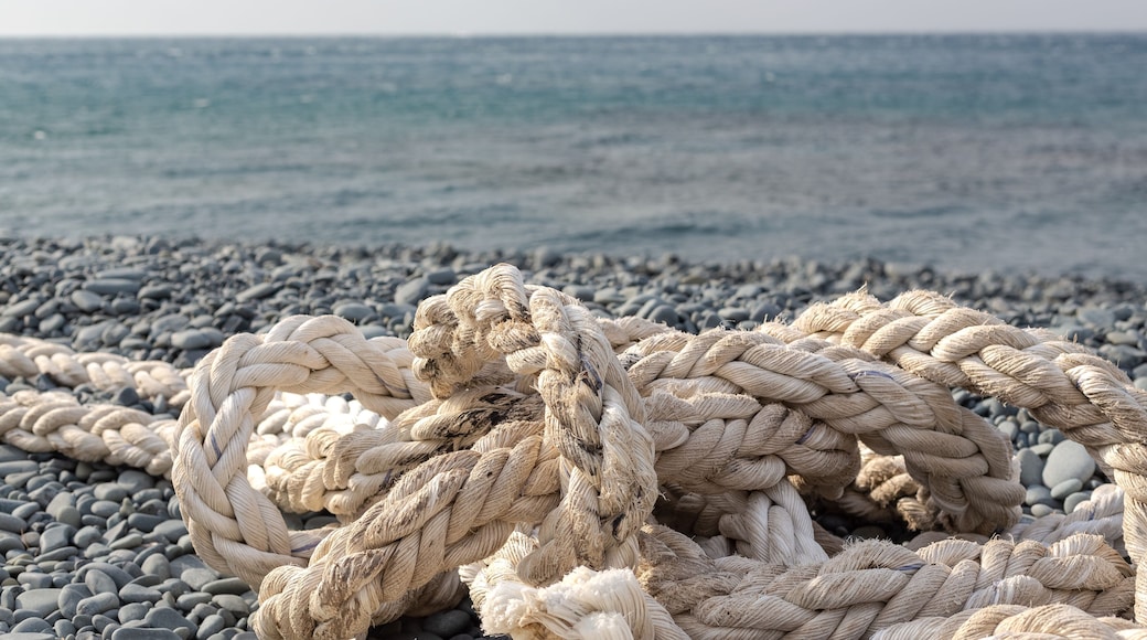 The ship's rope is in selective focus. Woven with thick bundles of threads, the ship's rope lies on a pebble beach. Türkiye, Samandağ, Hatay, Mediterranean coast.