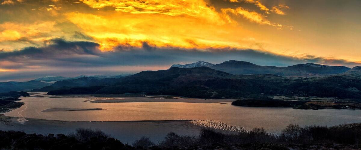 A lake surrounded by mountains during sunset.