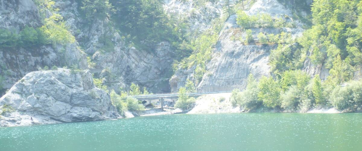 A bridge over a river with rocky cliffs and greenery.