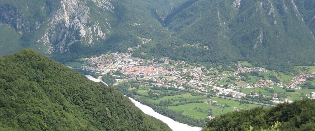 A valley with a river, surrounded by mountains and a small town.