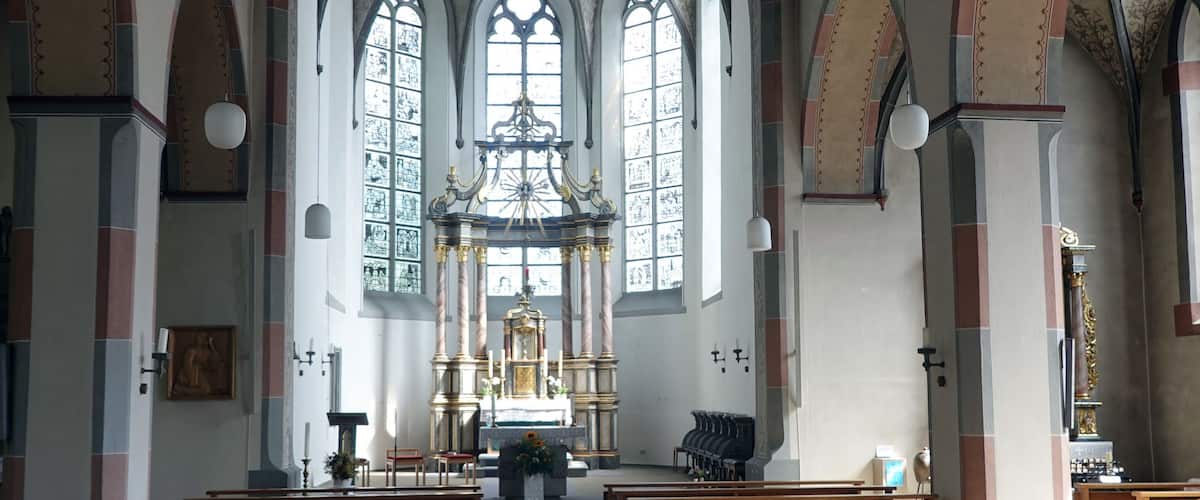 An interior of a church with arched ceilings, wooden pews, and a central altar.