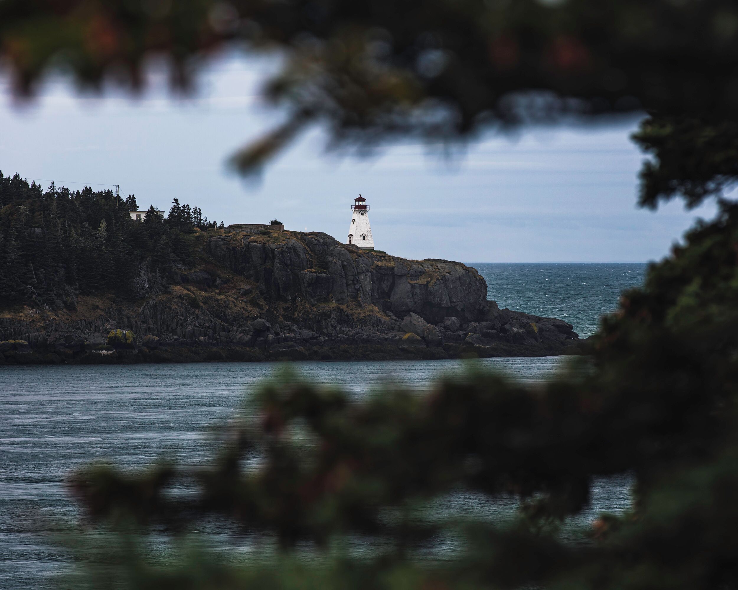 A lighthouse on a rocky cliff by the sea.