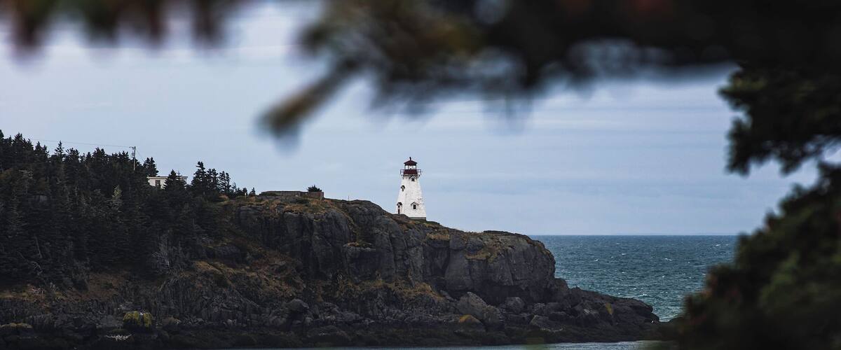 A lighthouse on a rocky cliff by the sea.