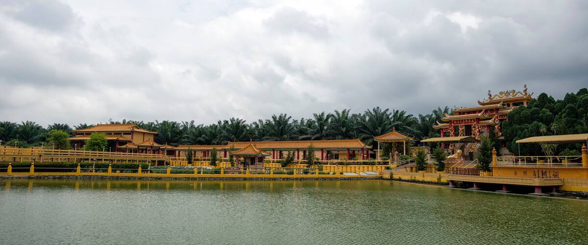 A traditional Chinese architectural complex with multiple buildings, a bridge, and a body of water.