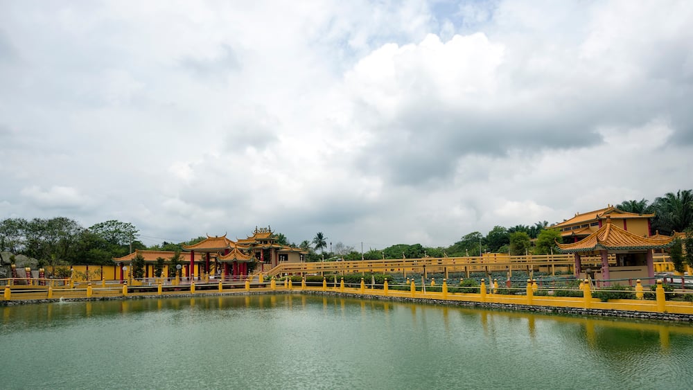 A traditional Chinese temple complex with golden roofs and a large pond.
