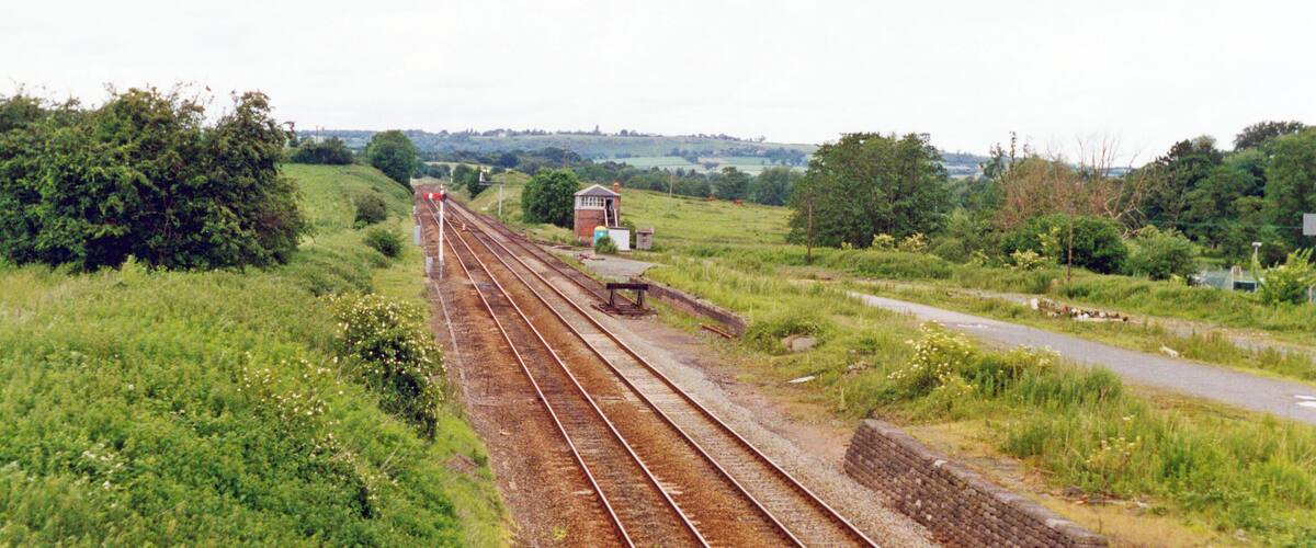 A railway track with a signal box and a small building in a rural setting.