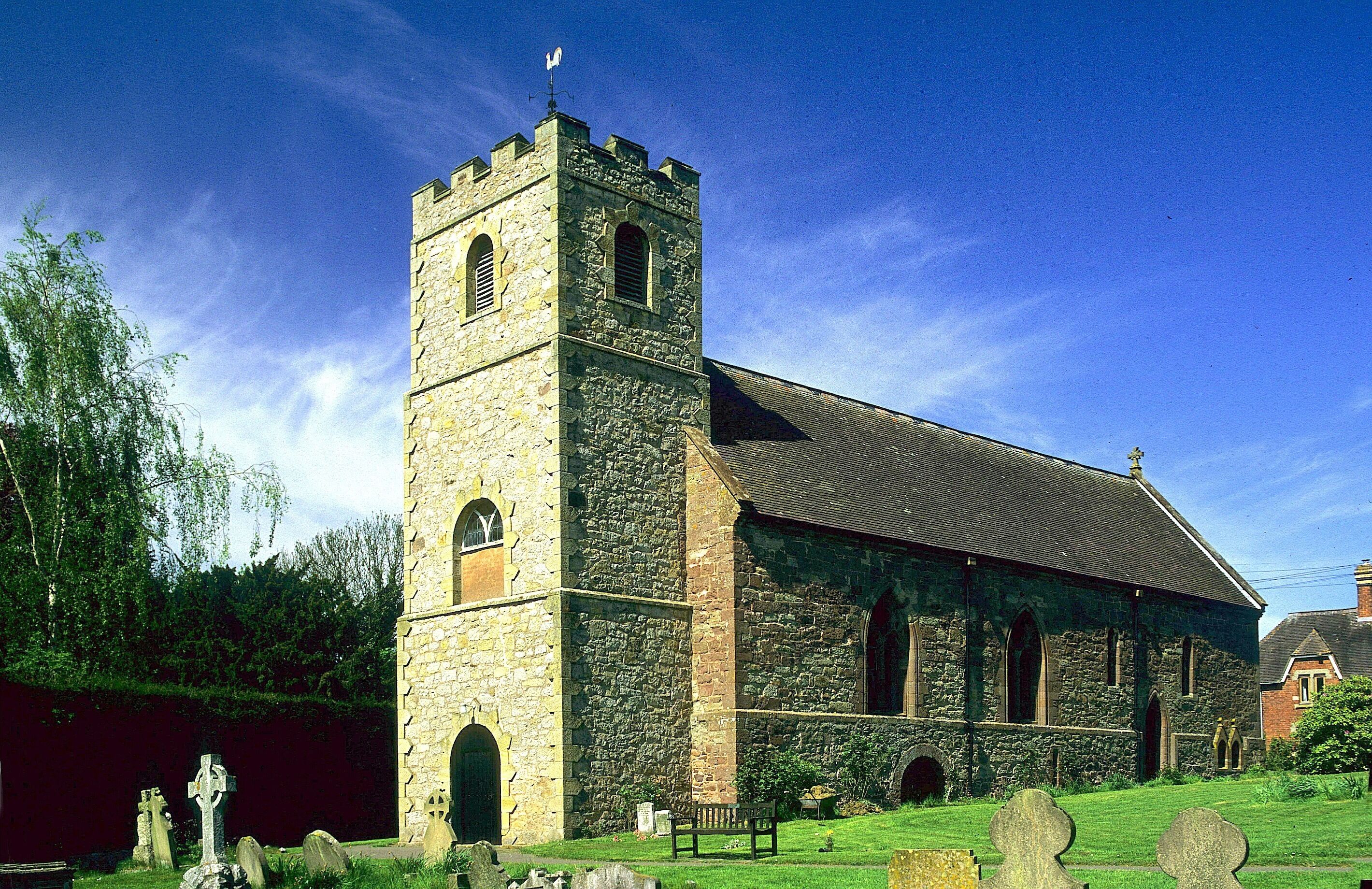A stone church with a bell tower and crosses in the foreground.