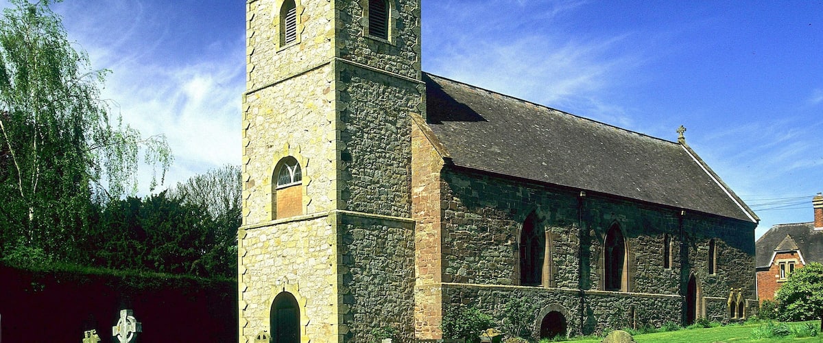 A stone church with a bell tower and crosses in the foreground.