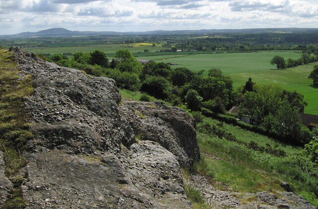 View from Lyth Hill These rocks are look a little like concrete, but they are conglomerate, which is composed of pebbles embedded in a sandy matrix. This is a Precambrian sedimentary rock dating from around 650 million years ago. The distant hill on the left is the Wrekin (407m)