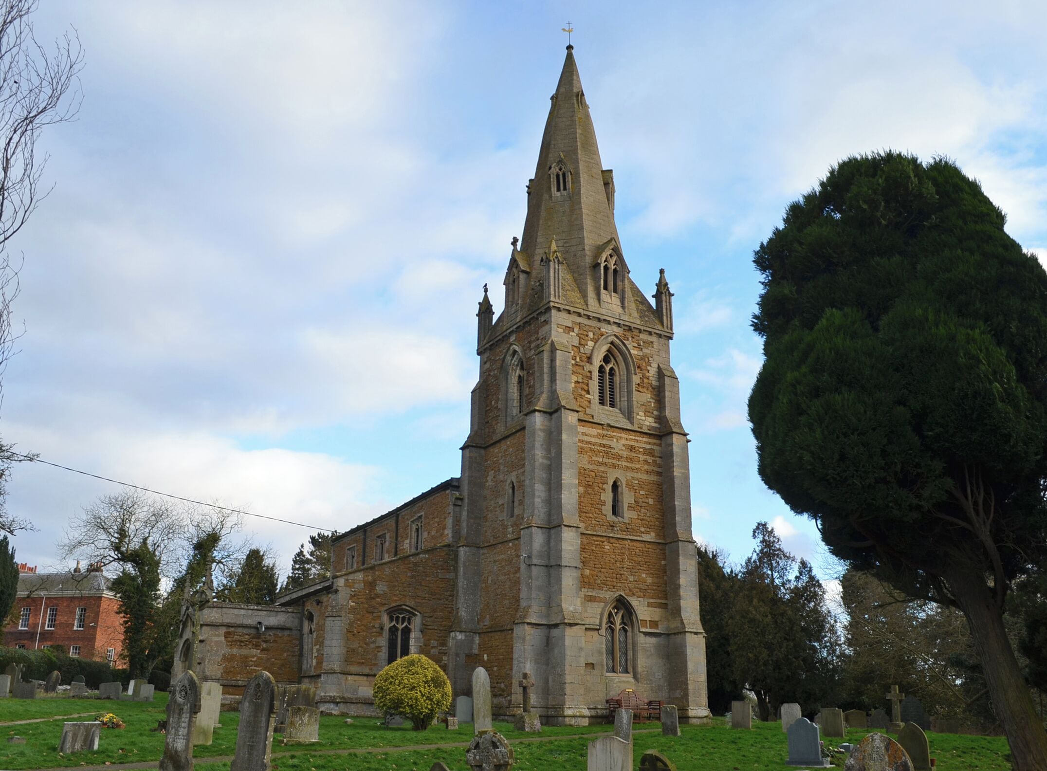 A church with a tall spire and stone walls.