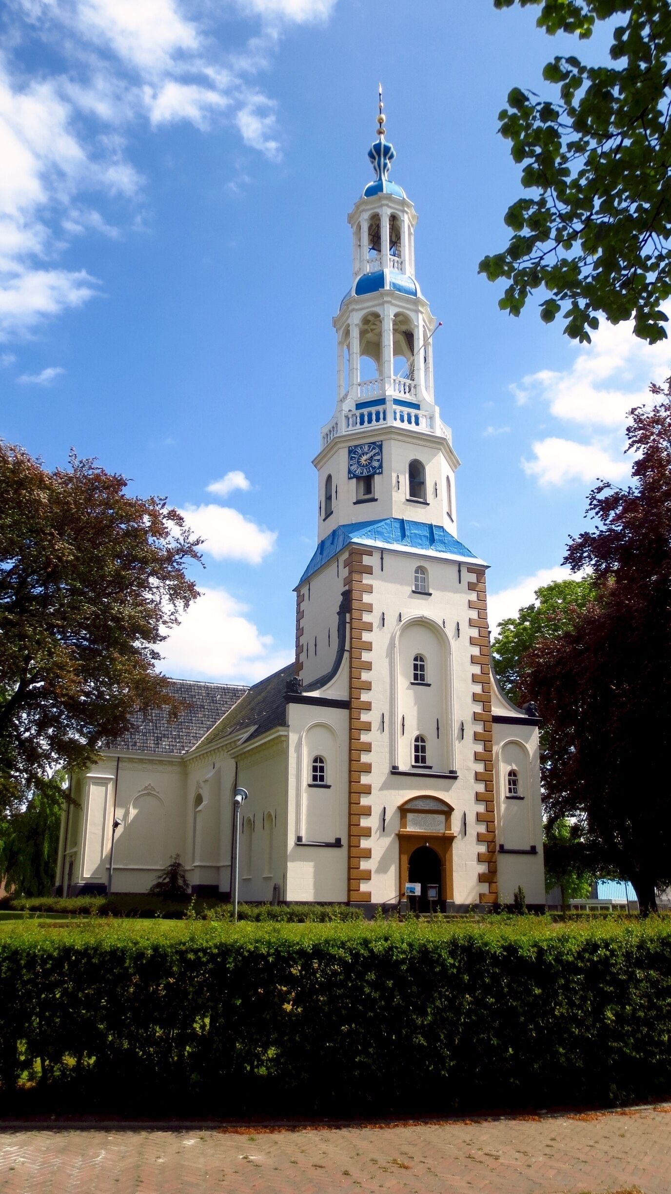 Een kerk met een hoge klokkentoren, een blauwe koepel en witte muren.