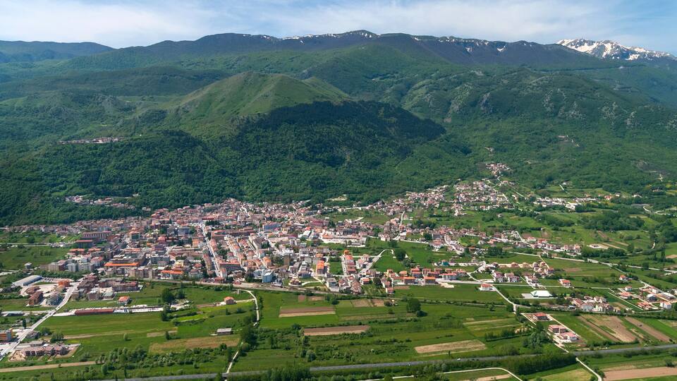A town nestled in a valley surrounded by green hills and mountains.