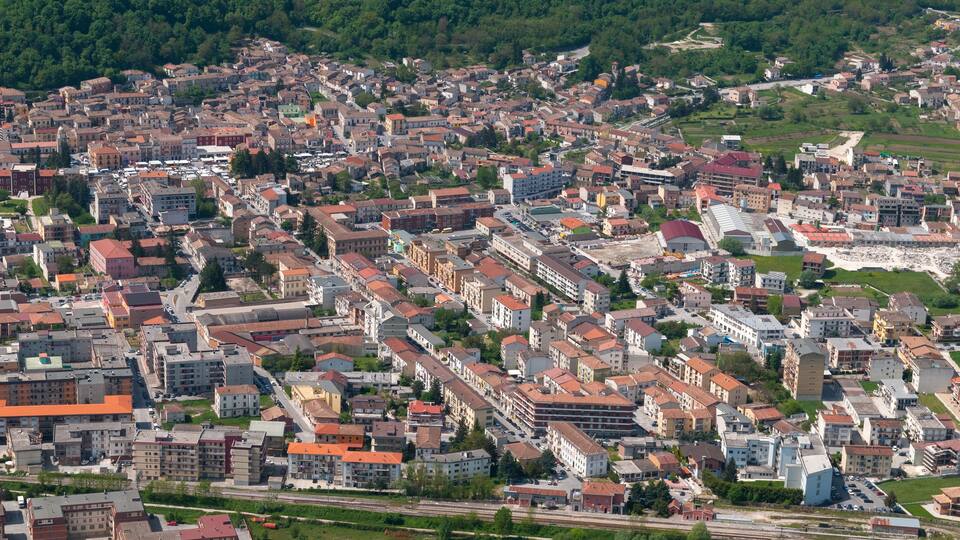 A densely packed urban area with numerous buildings and a railway track running through the center.