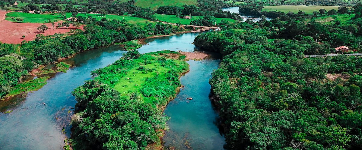 A river winding through a lush valley with green fields and scattered houses.