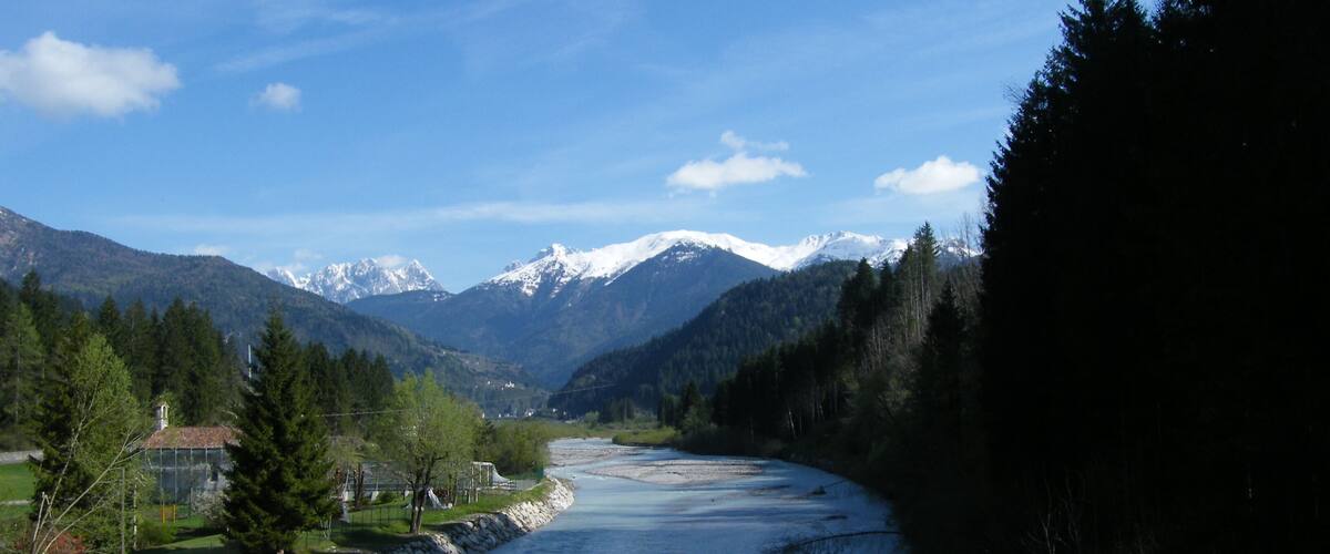 A river flowing through a valley with mountains in the background.