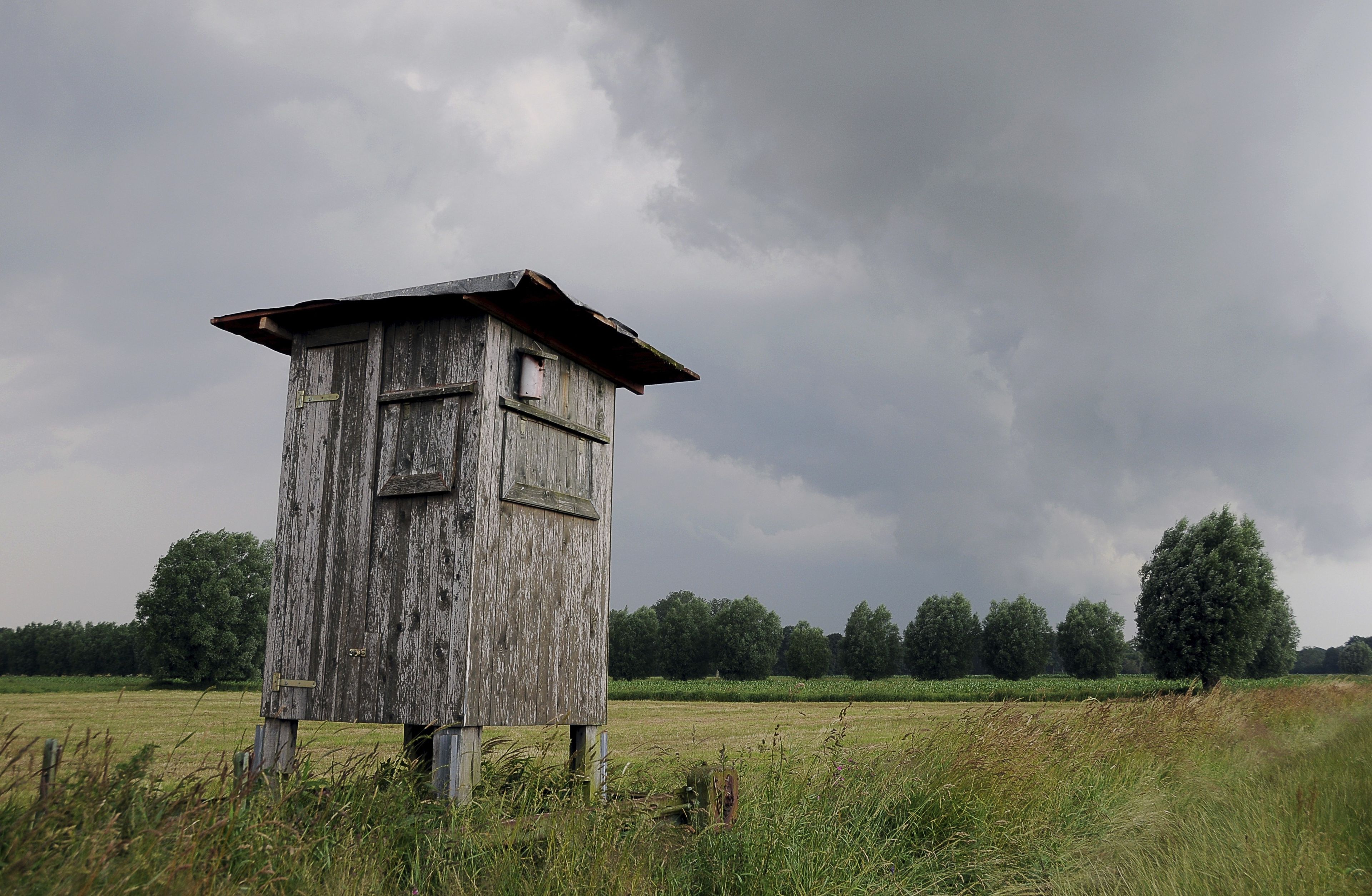 A weather station in a field with a cloudy sky.
